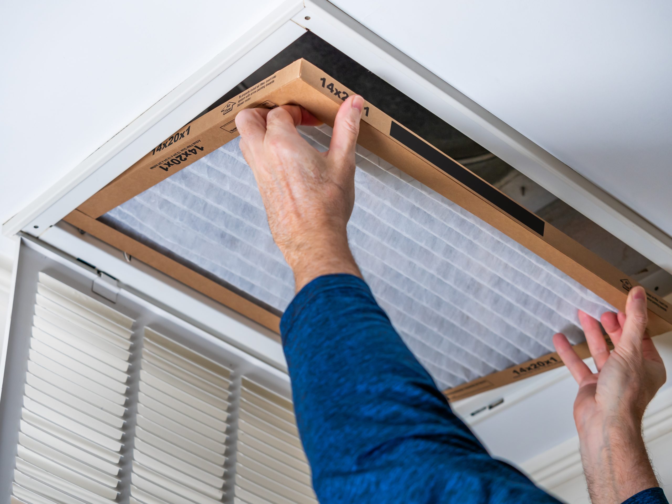 Man replacing dirty HVAC air filter in ceiling vent. Home air duct